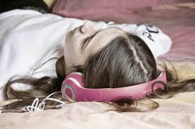 girl laying on the floor and wearing pink headphones